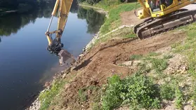 Bagger bereitet Einbau eines Sondenrohrs am Flussufer vor